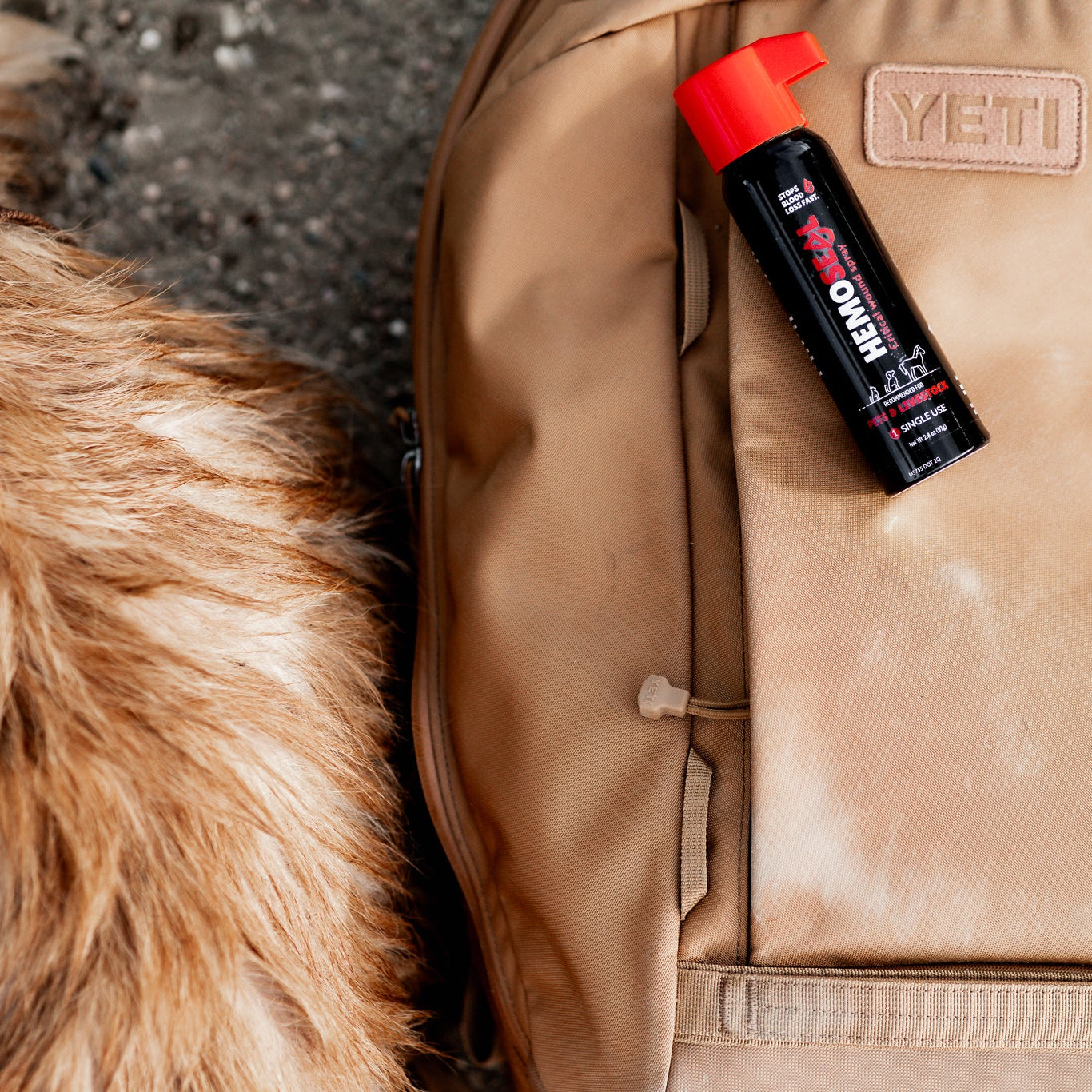 Hemoseal spray can with red nozzle on a beige backpack next to a furry animal.